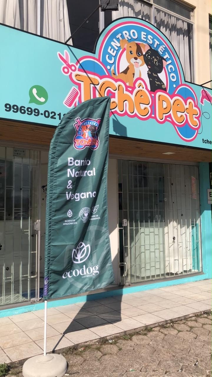 Fachada da Tchê Pet, com a placa turquesa e a bandeira do banho natural e vegano